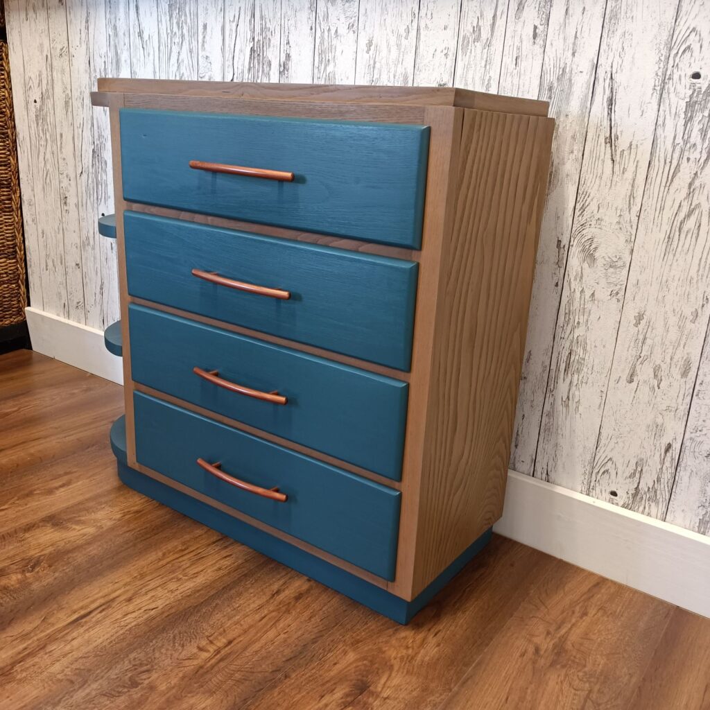 Holzkommode mit 4 Schubladen in blau und Kupfergriffen, links 3 Regale, von rechts
